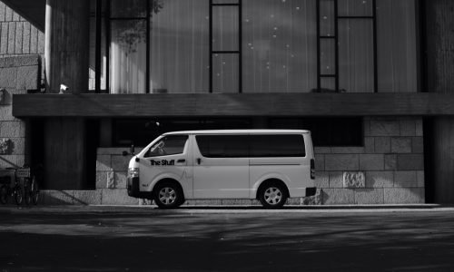 Black and white photo of a van parked outside a modern building in Taito, Tokyo.